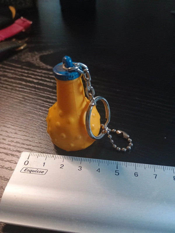 Porte clé en plastique représentant la célèbre bouteille ronde de la boisson à l'orange, Orangina