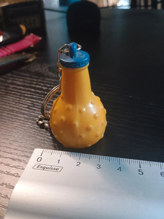 Porte clé en plastique représentant la célèbre bouteille ronde de la boisson à l'orange, Orangina